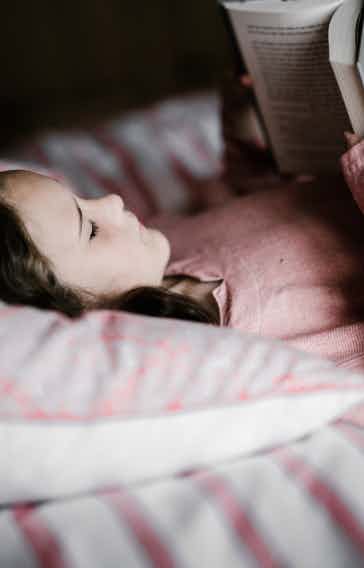 Child in bed reading a book