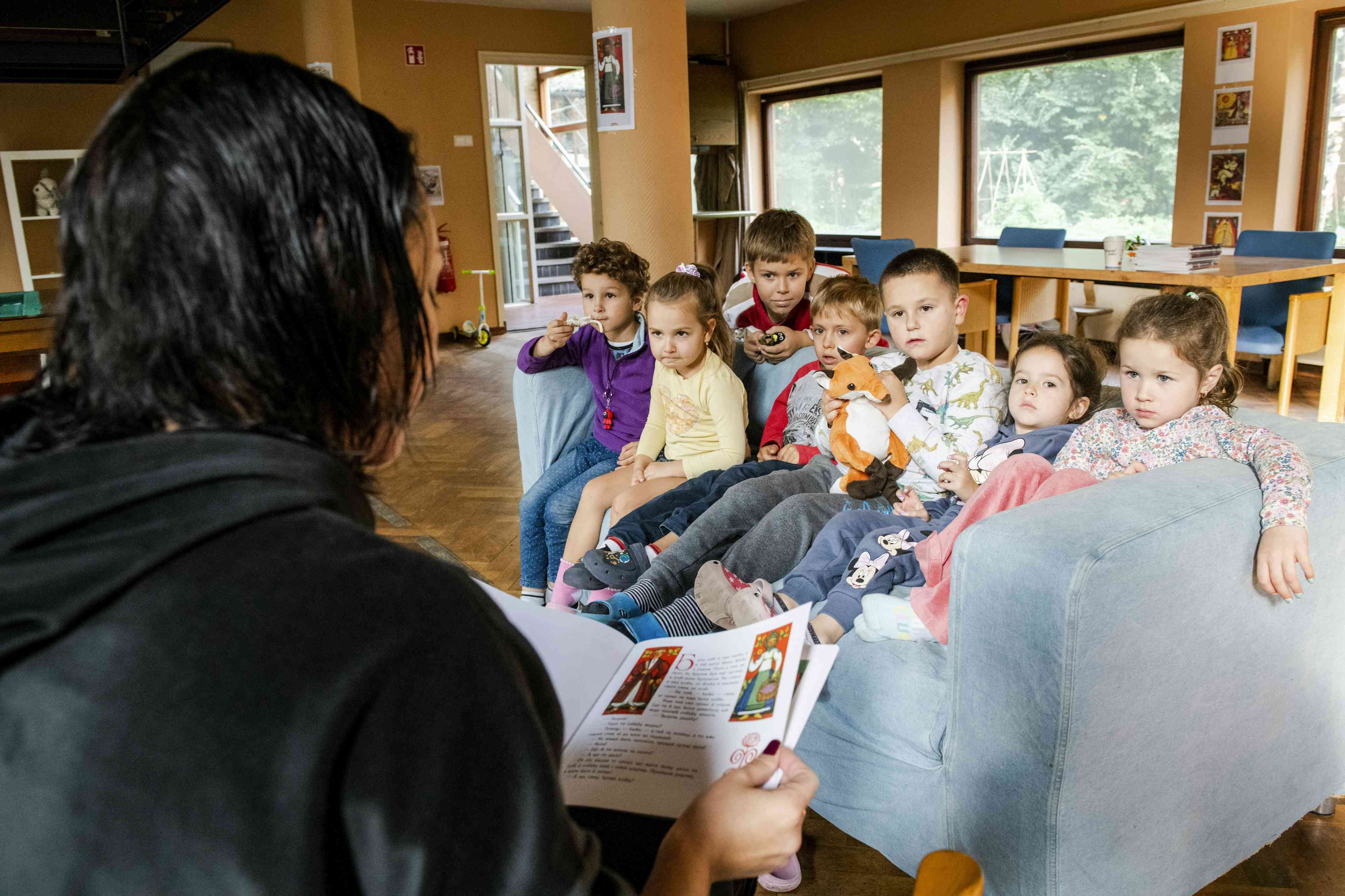 Woman reading a book to group of refugee children